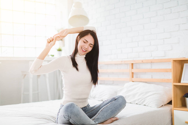 mooie jonge vrouw stretching en wakker in de slaapkamer - Foto, afbeelding