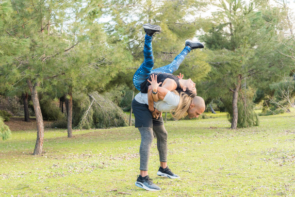 Fitness couple doing back to back lifting exercise in the park - Photo, Image