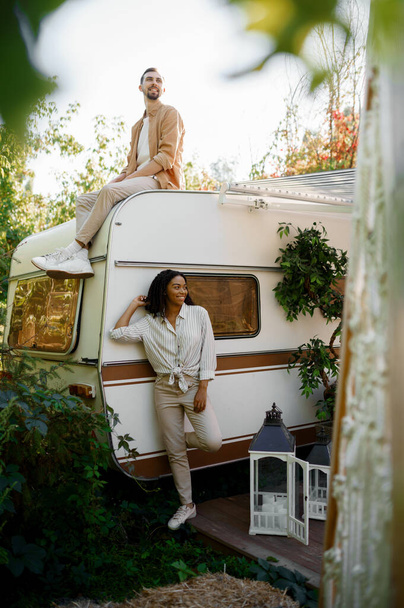 Happy love couple poses near rv, camping in a trailer. Man and woman travels on van, romantic vacations on motorhome, campers leisures in camping-car - Fotó, kép