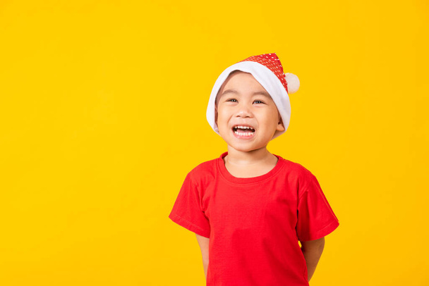 Kid dressed in red Santa Claus hat, Portrait of Asian little cute boy smile and excited the concept of holiday Christmas Xmas day or Happy new year, studio shot isolated on yellow background - Фото, зображення