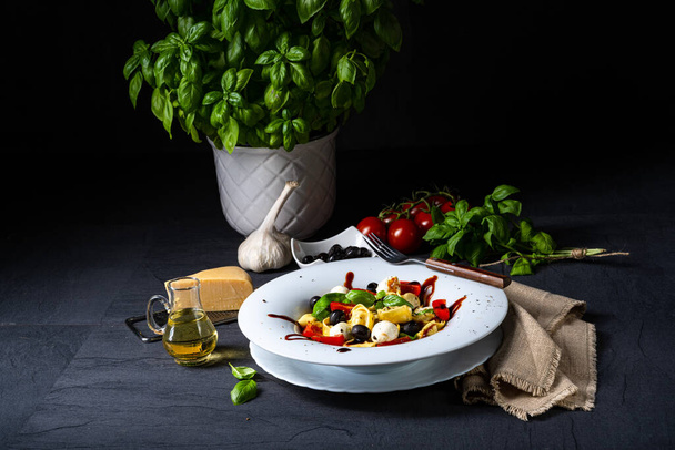 salad with tomato, pepper, onions and basil on a black background. - Zdjęcie, obraz