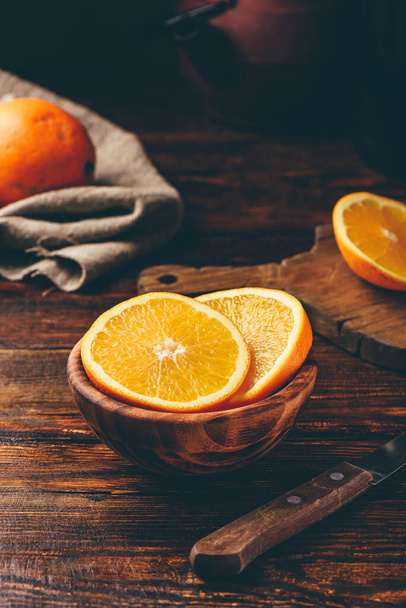 Slices of orange in a rustic wooden bowl - Φωτογραφία, εικόνα