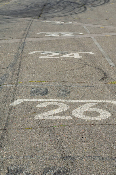 Na chodníku jsou namalovaná bílá čísla. Výchozí místa pro motokáry. Startovní mřížka je místem pro motokáry, které mají být postaveny ve startovním pořadí. Motokárová dráha. Dětský motorsport, soutěž - Fotografie, Obrázek