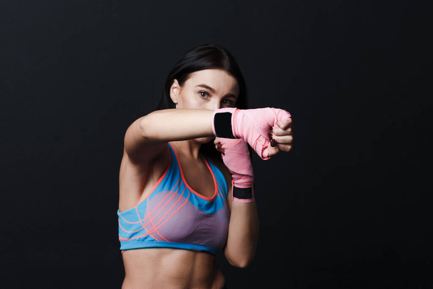 Sportsman muay thai woman boxer posing in training studio at black background. - Fotoğraf, Görsel