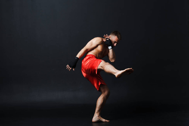 Sportman muay thai man bokser houding op zwarte achtergrond - Foto, afbeelding