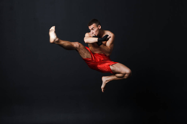 Sportsman muay thai man boxer stance at black background - Valokuva, kuva