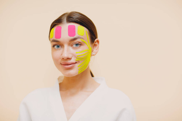 Gyönyörű nő alkalmazó szalag emelő kezelés az arcon - Fotó, kép