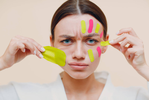 Krásná žena nanášení lepicí pásky ošetření na obličej - Fotografie, Obrázek