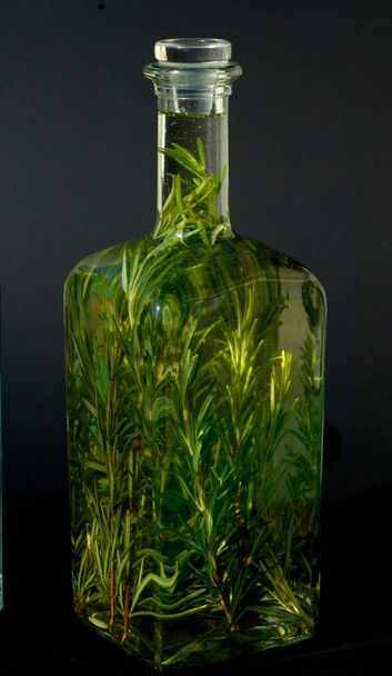 glass bottle with green leaves on a black background - Photo, image
