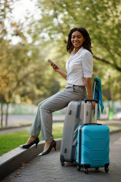 Woman with two suitcases on walkway in summer park. Female traveler with luggage leisures outdoors, passenger with bag resting in nature. Girl with baggage relax on city alley - Foto, Bild