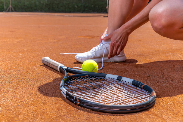 tying shoelace tennis shoes on the court, racket and ball. - Foto, Bild