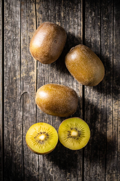 Halved ripe yellow kiwi fruit on old wooden table. Top view. - Fotoğraf, Görsel