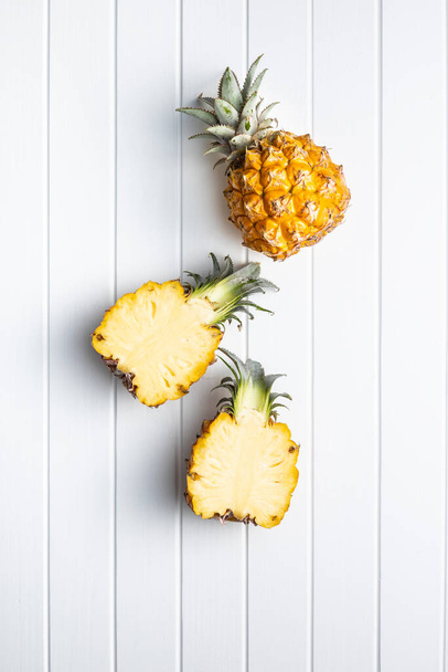 Ripe baby pineapple. Halved mini pineapple on white wooden table. Top view. - Foto, Imagen