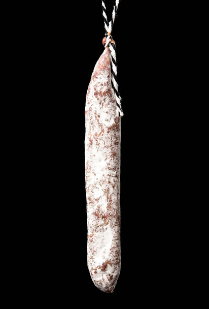 whole stick of raw smoked sausage with white mold isolated on a black background, close up - Photo, image