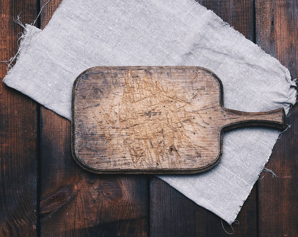 old brown rectangular wooden kitchen cutting board and gray linen napkin on the table, top view - Foto, Imagen