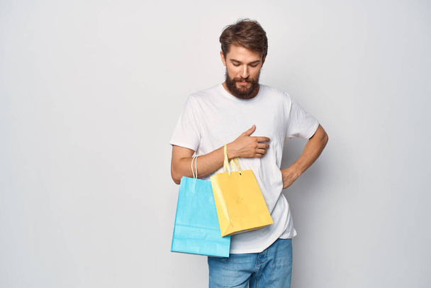 Wesoły mężczyzna w białej koszulce z paczkami emocji zakupowych styl życia - Zdjęcie, obraz