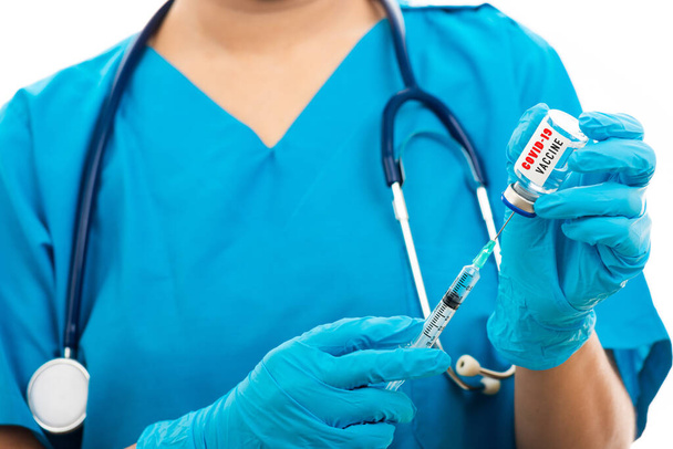 Female nurse with stethoscope puts on rubber gloves and wear medical face mask, woman doctor in blue uniform holding syringe . and COVID-19 vaccine, isolated white background, medical health concept - Photo, image