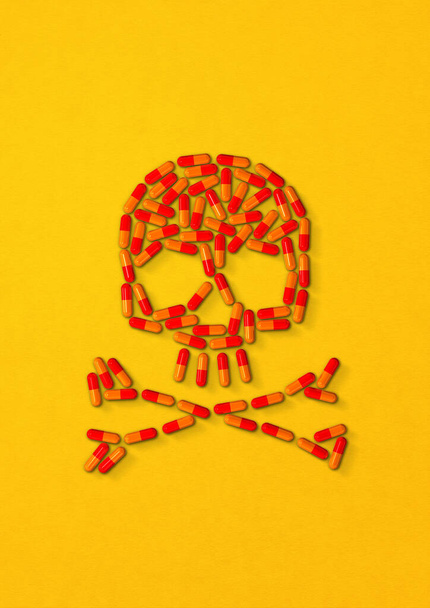 Skull made of orange capsule pills isolated on yellow background. 3D illustration - Fotó, kép