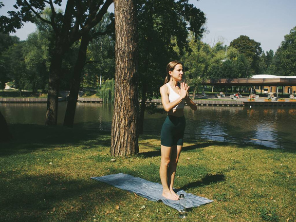 yoga en el parque, poses, assanas, estiramientos y flexibilidad, ropa de yoga - Foto, imagen