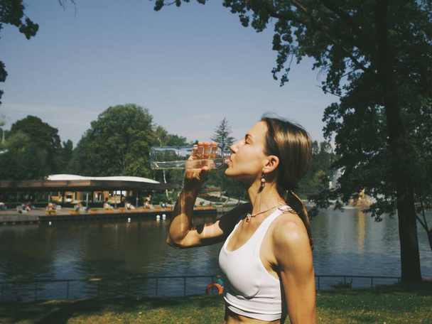 молода жінка після тренування в парку п'є воду
 - Фото, зображення