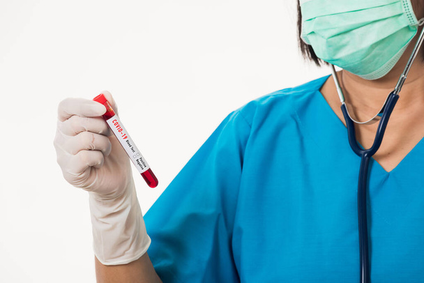 Krankenschwester in blauer Uniform trägt eine Maske mit einer Probe Coronavirus-Testblut im Labor zur Analyse isoliert auf weißem Hintergrund, Medikament COVID-19 Pandemieausbruchskonzept - Foto, Bild