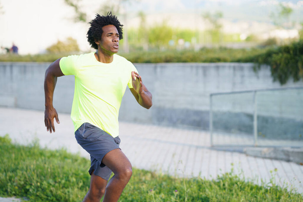 Uomo atletico nero che corre in un parco urbano. - Foto, immagini