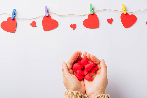 Valentine's day and birthday. Woman hands holding red heart present decorated surprise on white background, Female's hand hold gift heart on hands, Top view flat lay composition - Foto, Imagen