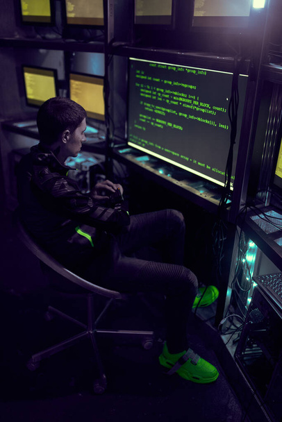 Hacker is working with computer typing text in dark room. - Fotó, kép