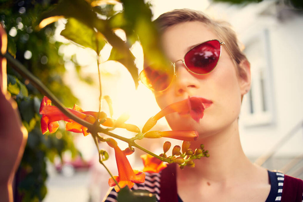 όμορφη γυναίκα σε εξωτερικούς χώρους φορώντας γυαλιά ηλίου λουλούδια close-up - Φωτογραφία, εικόνα