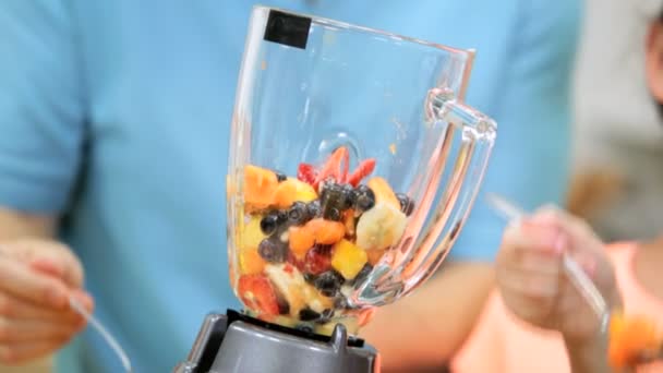 Family putting fruit into blender - Filmati, video