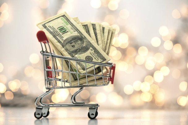 Shopping cart filled with one hundred dollars with bokeh background, business and finacial concept copy space - 写真・画像