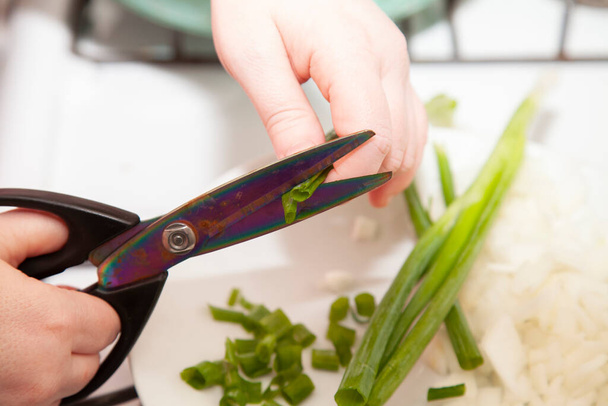 Cutting green onions into small pieces with kitchen shears - 写真・画像