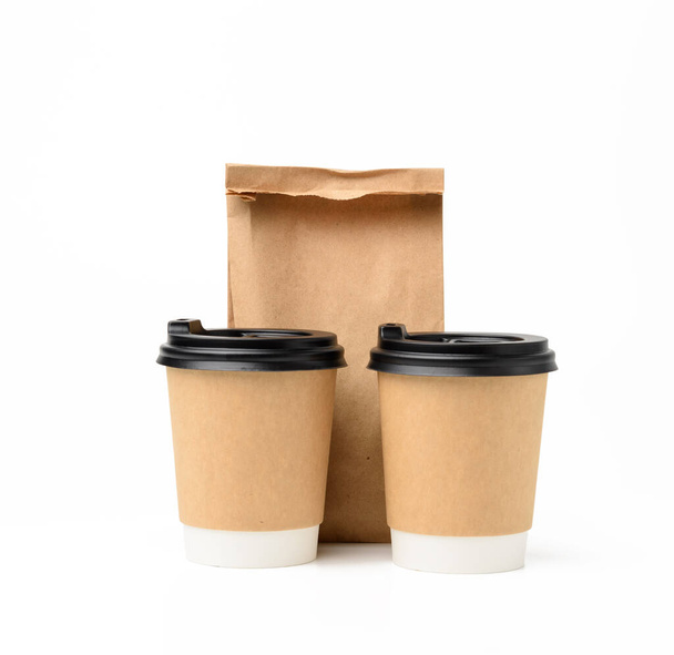 two brown paper cups with a plastic lid and a paper bag for food, ecological recyclable food packaging on a white background - Fotoğraf, Görsel