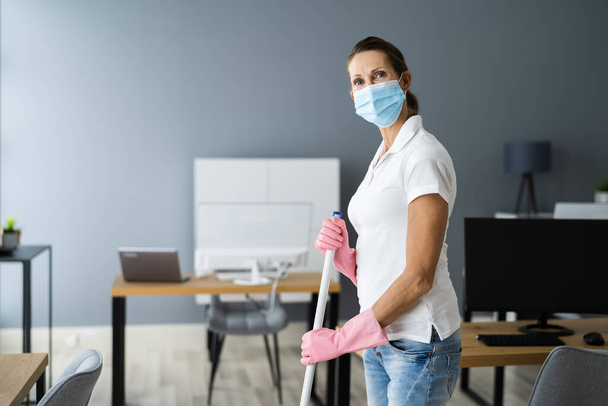 Female Janitor Mopping Floor In Face Mask In Office - 写真・画像