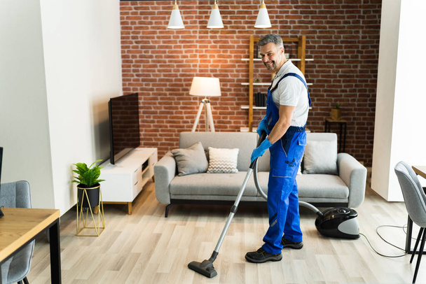 Man In Uniform Vacuuming House Floor. Cleaning Home - Фото, изображение