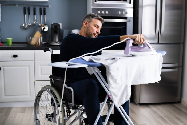 Handicapped Disabled Man In Wheelchair Ironing Clothes - Valokuva, kuva