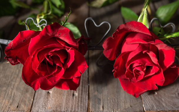 Two red roses with hearts on dark wooden boards. Background for valentine's day greetings with space for your text. Close-up. - Фото, зображення