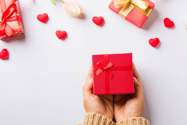 Valentine's day and birthday. Woman hands holding gift or present box decorated and red heart surprise on white background, Female's hand hold gift box package in craft paper Top view flat lay - Valokuva, kuva