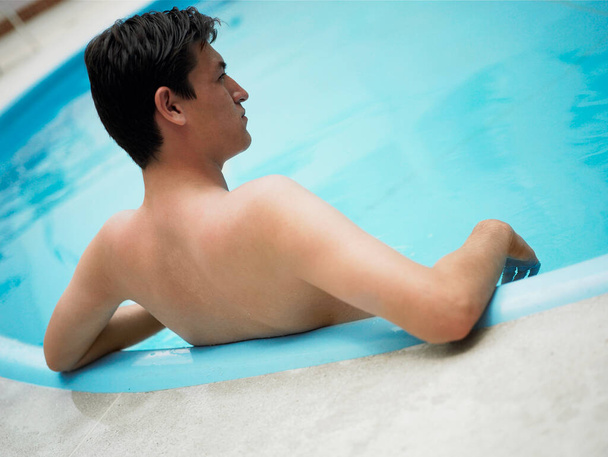 young man relaxing in swimming pool - 写真・画像