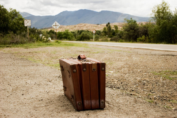 old suitcase with suitcases and a bag on the background of the road - 写真・画像