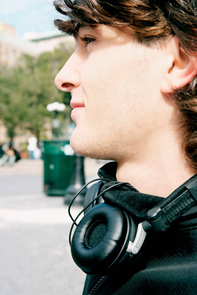 young man with headphones listening to music on city street - Foto, Imagen