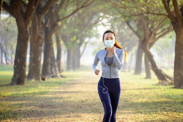 young woman in face mask and running in the park - Photo, Image