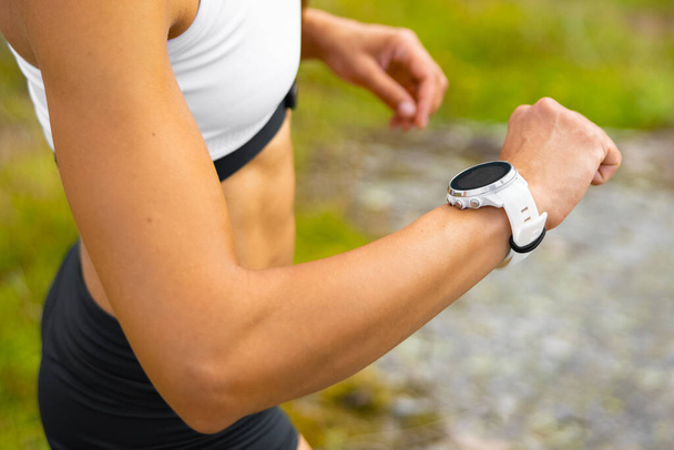Close-up of athletic woman using fitness smart watch device under workout - Photo, Image