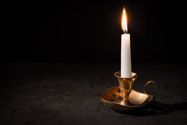Burning candle  in vintage candlestick on black background. Copy space for your text. - Foto, Imagem