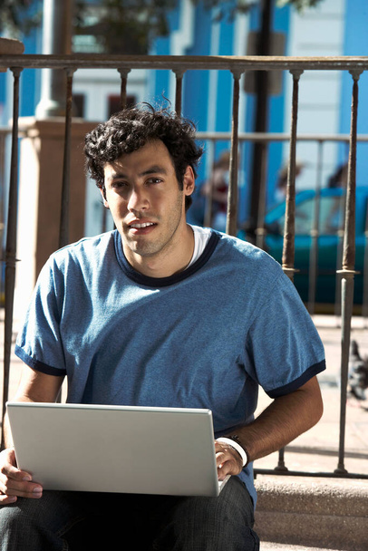 young man sitting on bench and working on laptop - Foto, imagen