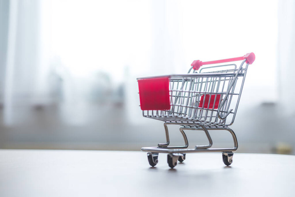 Online-Shopping and parcel service concept: Miniature shopping cart and white box - 写真・画像