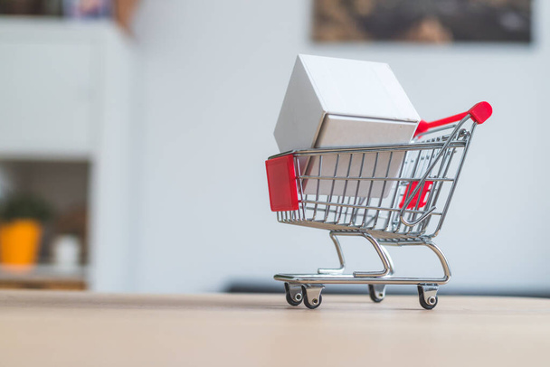 Online-Shopping and parcel service concept: Miniature shopping cart and white box - Fotó, kép