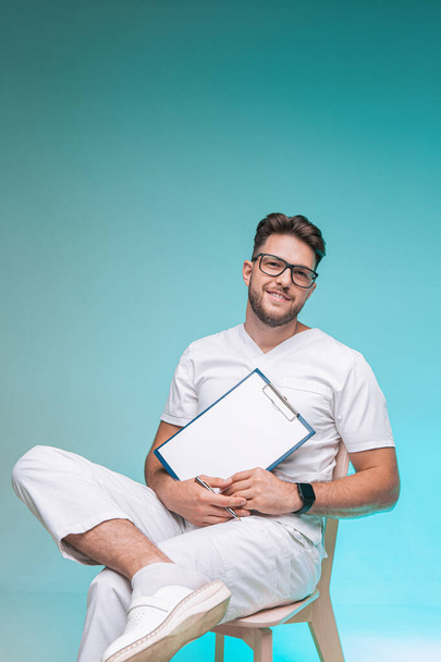 Smiling young male physician successful handsome practitioner in glasses with blank space sheet for doctor report - Photo, Image