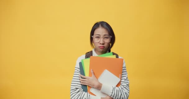 Unhappy Asia lady freelance worker with casual cloth holding work file feeling boring and tired with overwork and exited with advertise in copy space isolated on the yellow background. - Footage, Video