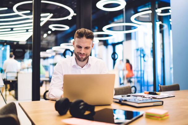 Smart casual male freelancer smiling during laptop messaging with distance colleagues, happy skilled man searching positive video while working remotely on startup project connecting to wifi internet - Fotoğraf, Görsel